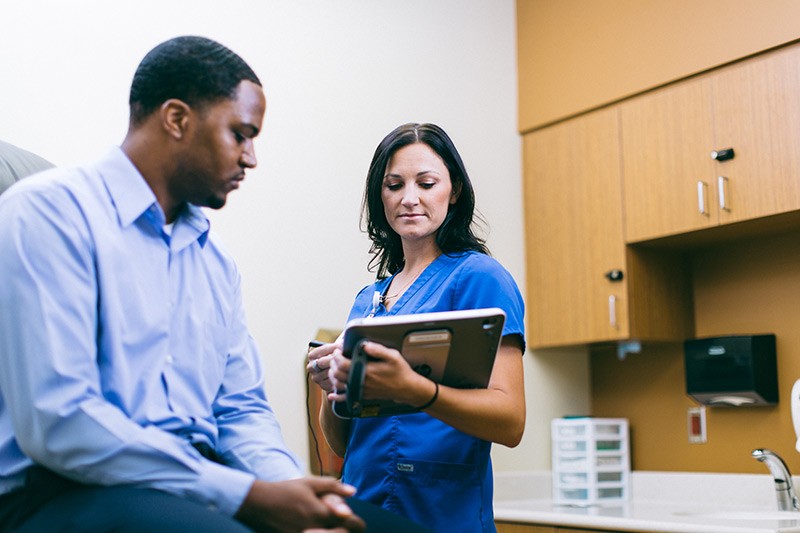 Nurse with patient in examination room using tablet computer